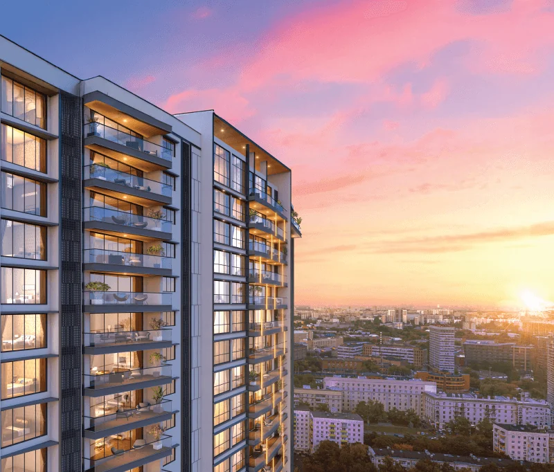 Corner of the Purva Orient Grand façade at sunset, showing stacked glass-railed private decks above the Central Bengaluru skyline