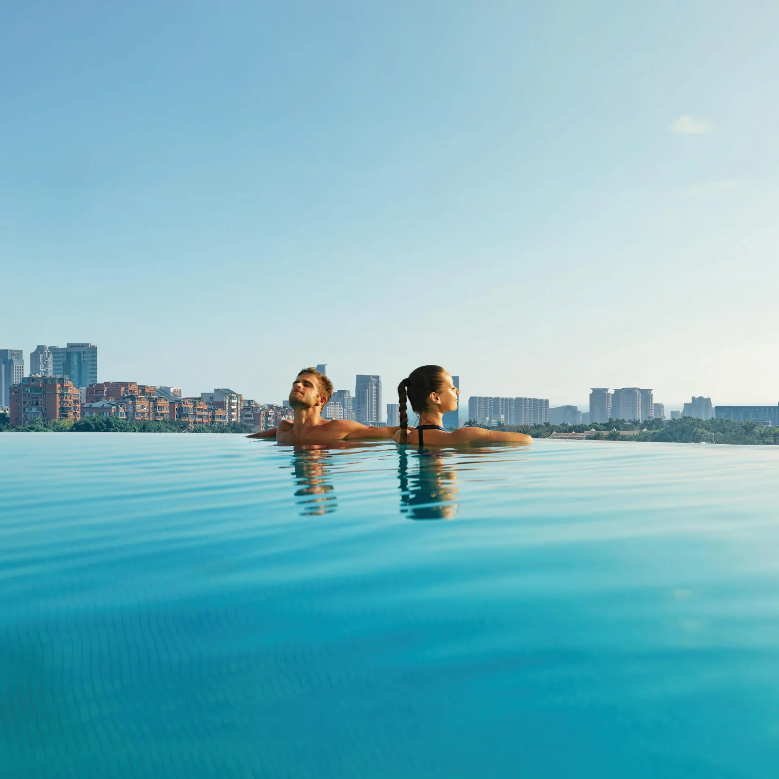 Residents in the infinity pool at the 25th level of Purva Orient Grand, with the city skyline beyond