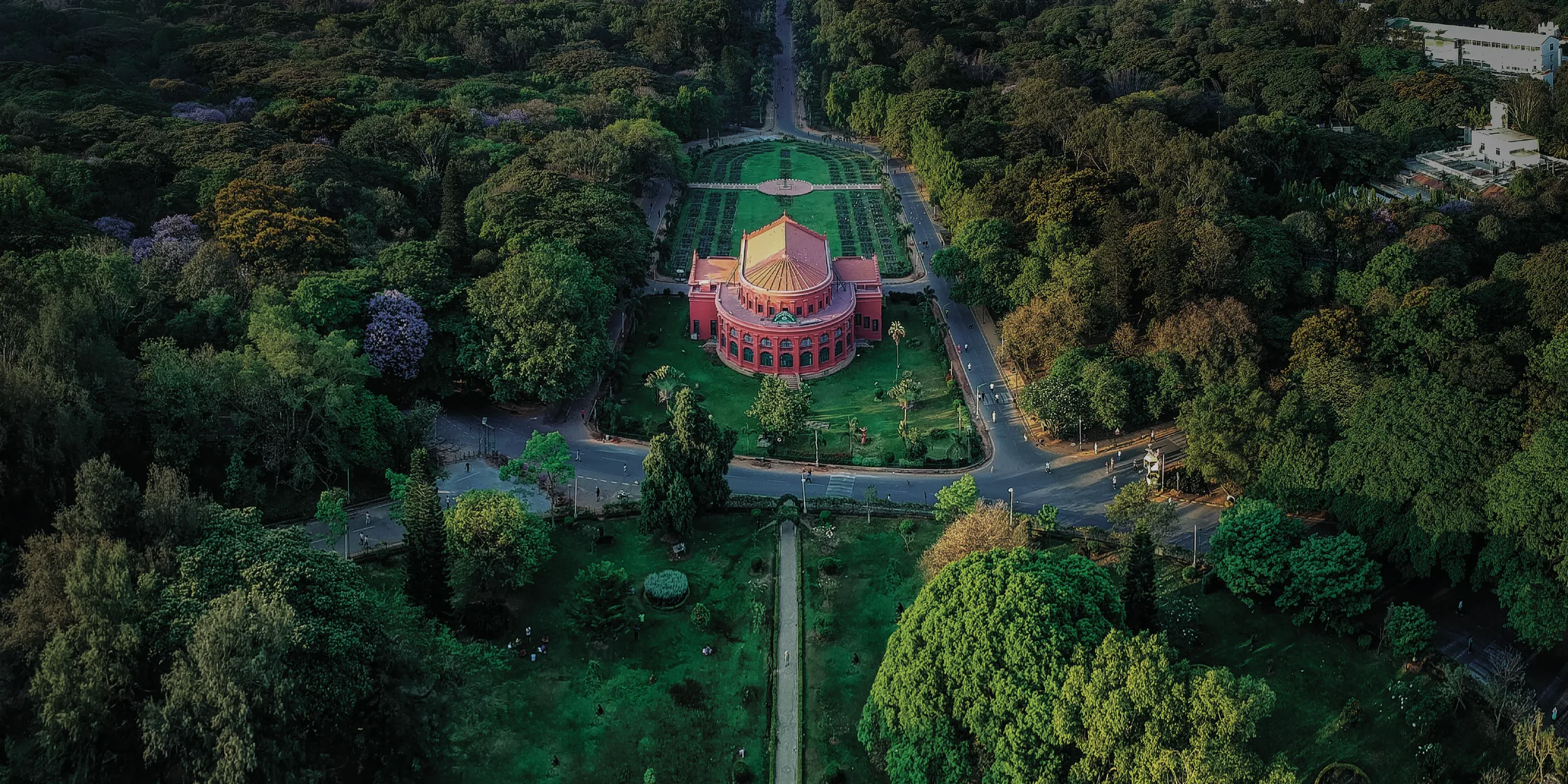Aerial view of the red State Central Library building amid the dense tree canopy of Cubbon Park, Central Bengaluru