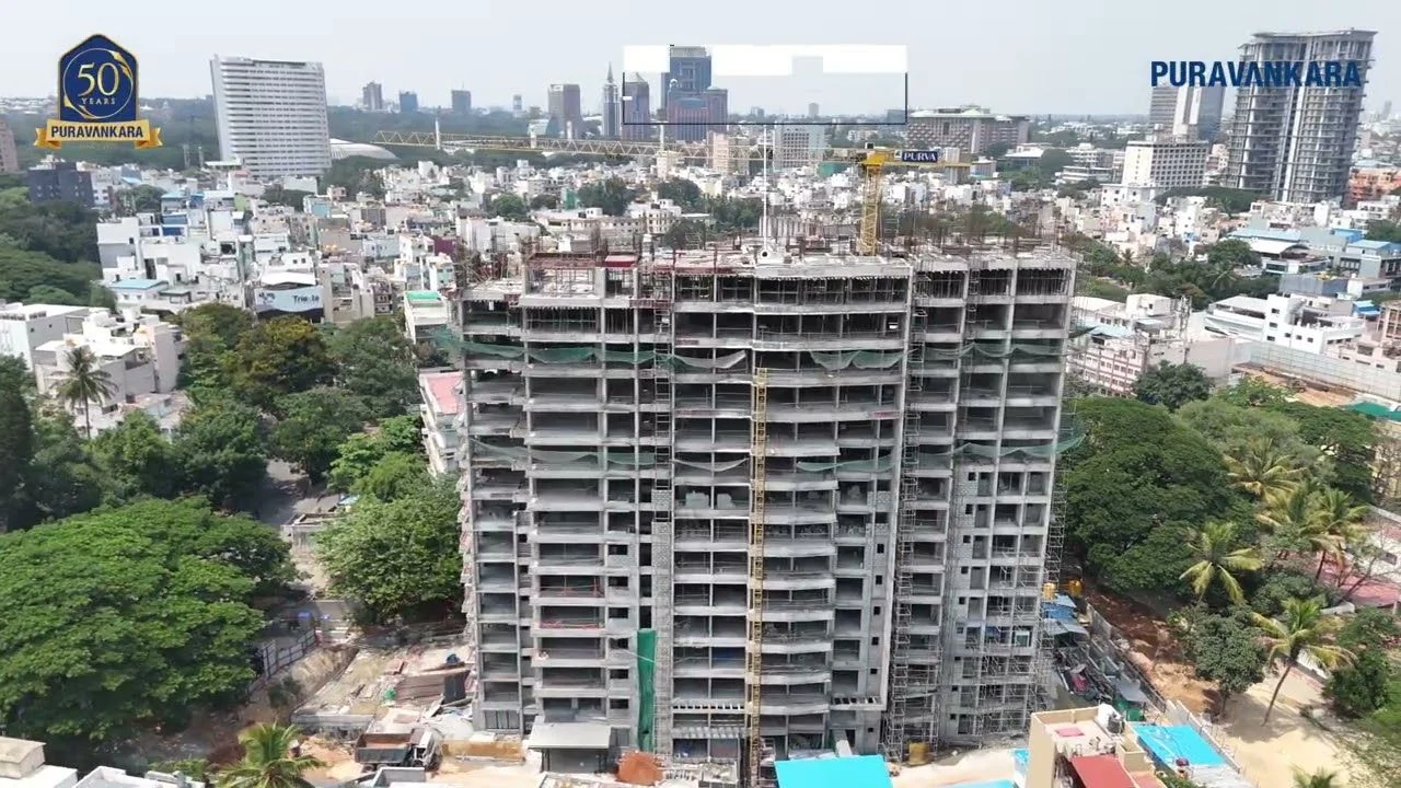 Aerial construction-status photograph of the Purva Orient Grand tower's concrete frame on Lal Bagh Main Road, published by Puravankara, with Central Bengaluru's skyline behind